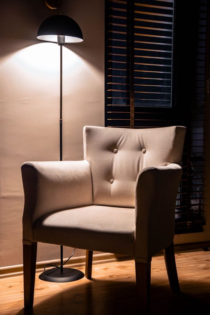 pexels-photo-27076715 Inviting white armchair under an illuminated floor lamp in a stylish modern living space.
