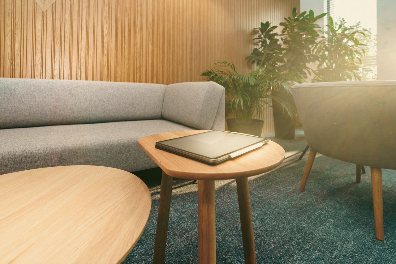about-01 Stylish and cozy home office setup with sofa, wooden tables, and abundant natural light.